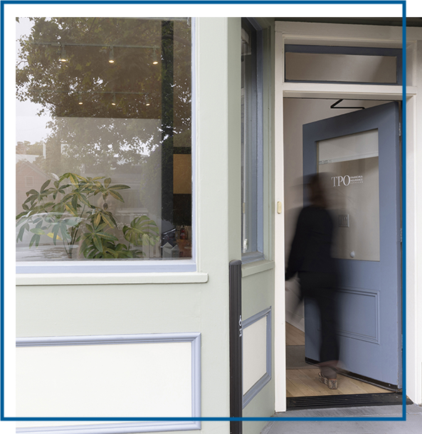 A person enters an office through a blue door with “TPO” printed on the glass.