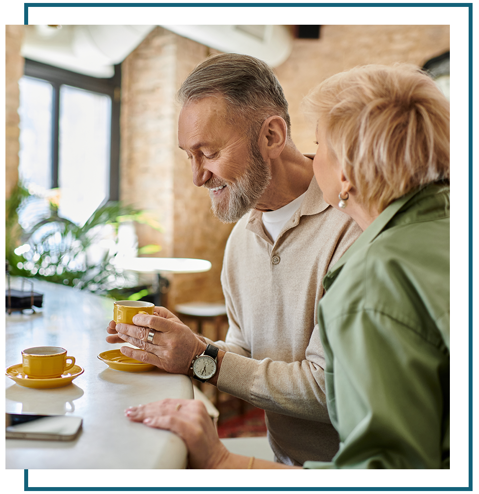 An older couple enjoying coffee together at a café, smiling and sharing a moment.