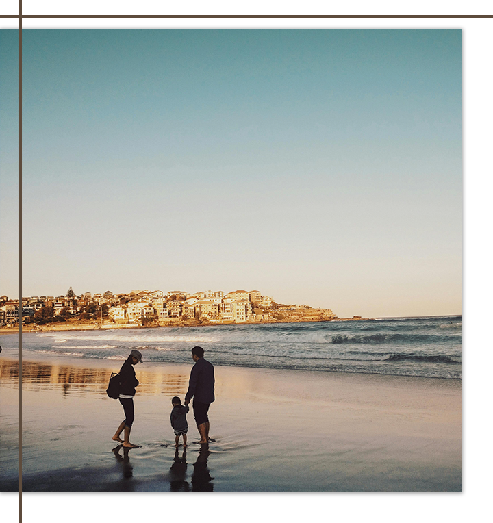 A family walking hand in hand along a beach at sunset.