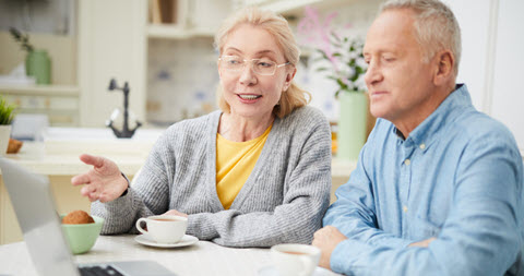 Senior couple sitting at the table with a laptop