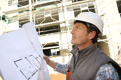 Business Owner looking at a blueprint wearing a hard hat