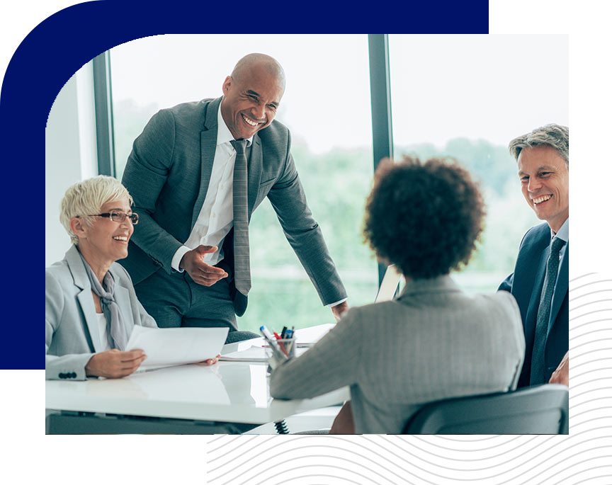 Smiling group of professionals in a modern conference room engaged in conversation around a table.