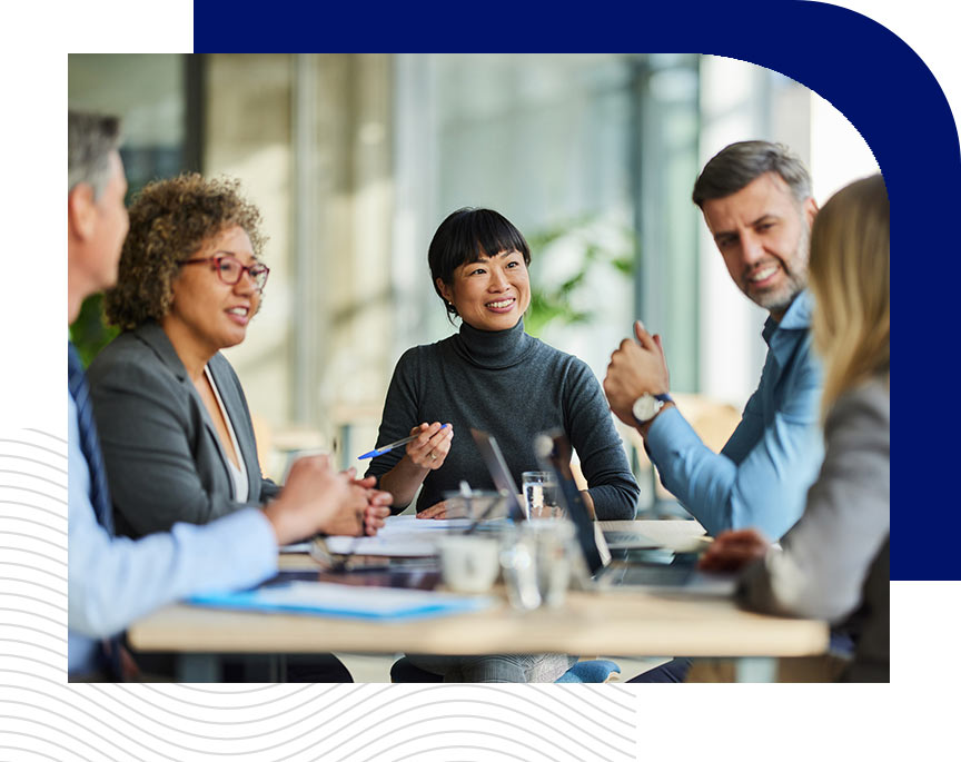 Diverse business team having a discussion in a bright, modern office with large windows and glass walls.