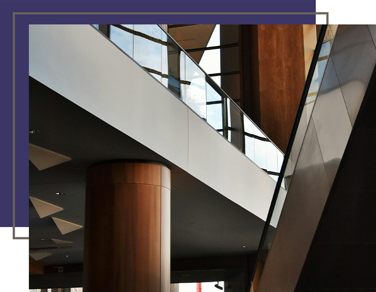 Interior view of a modern building featuring sleek architectural lines, glass railings, and warm wood finishes.