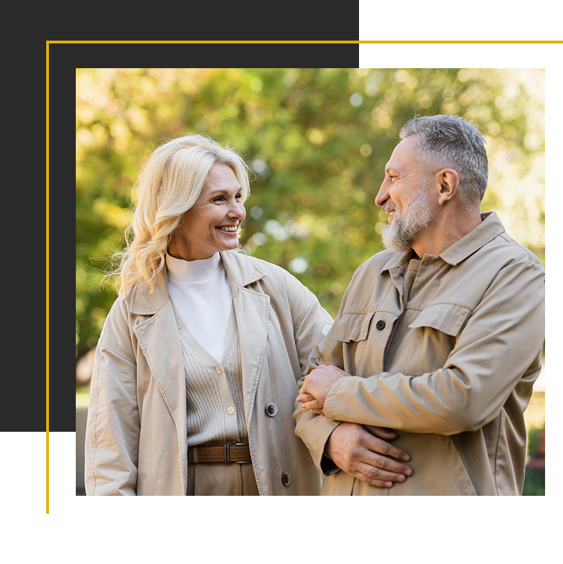 A smiling couple walks together outdoors, enjoying each other’s company