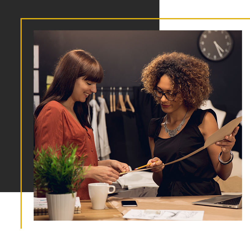 Two colleagues collaborate in a creative workspace, reviewing design materials and sharing ideas