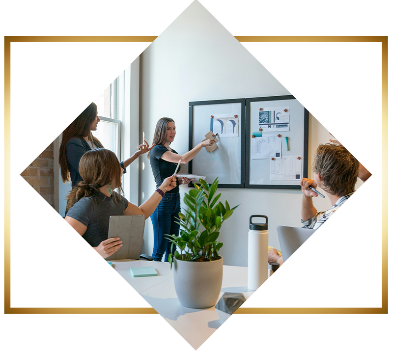 Team collaborating in a meeting as a presenter points to design ideas on a wall.